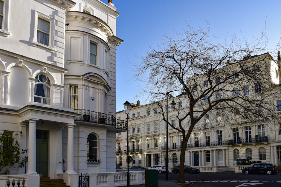 A multi-story red brick building with distinctive turret-like towers topped with grey domed roofs, located at the corner of a street in Ladbroke Grove. The building features large windows with white f